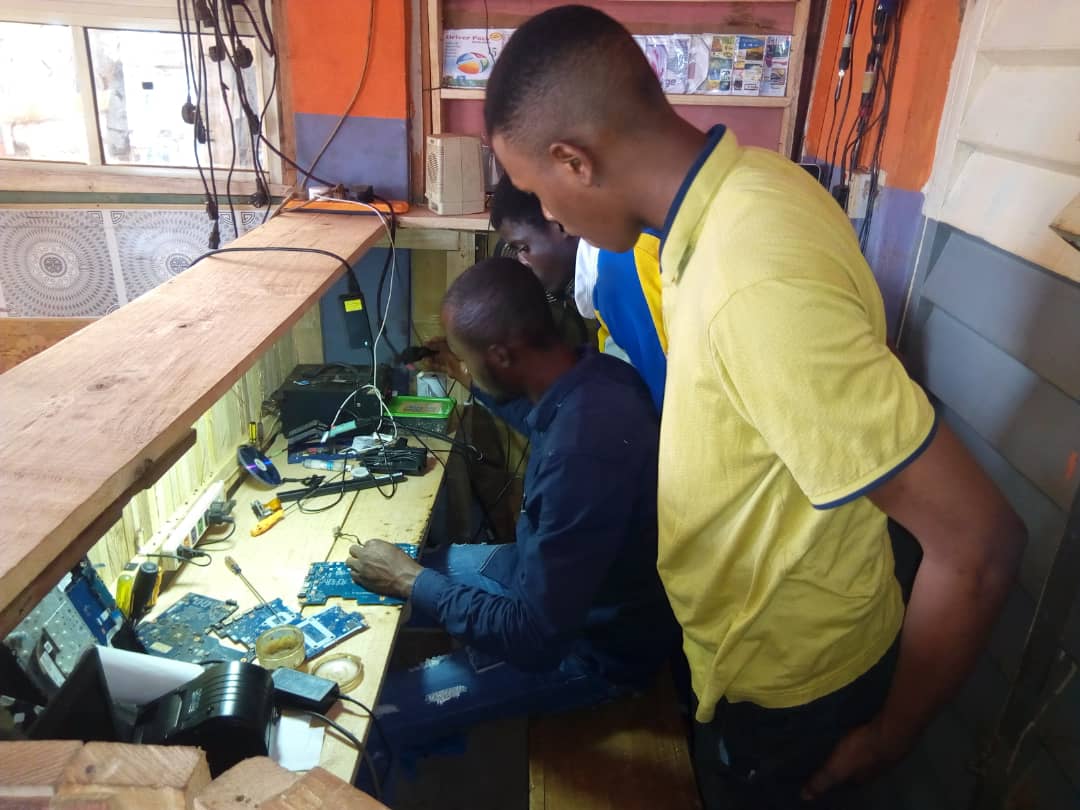 CEO Bigtoyo Computer Technology, Ijebu Ode repairing a laptop while some of his students look on.